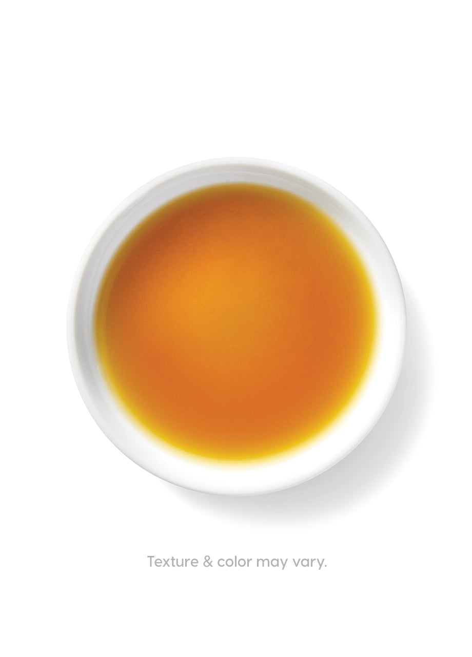 Bowl containing a golden-brown liquid, likely chicken bone broth, on a white background.