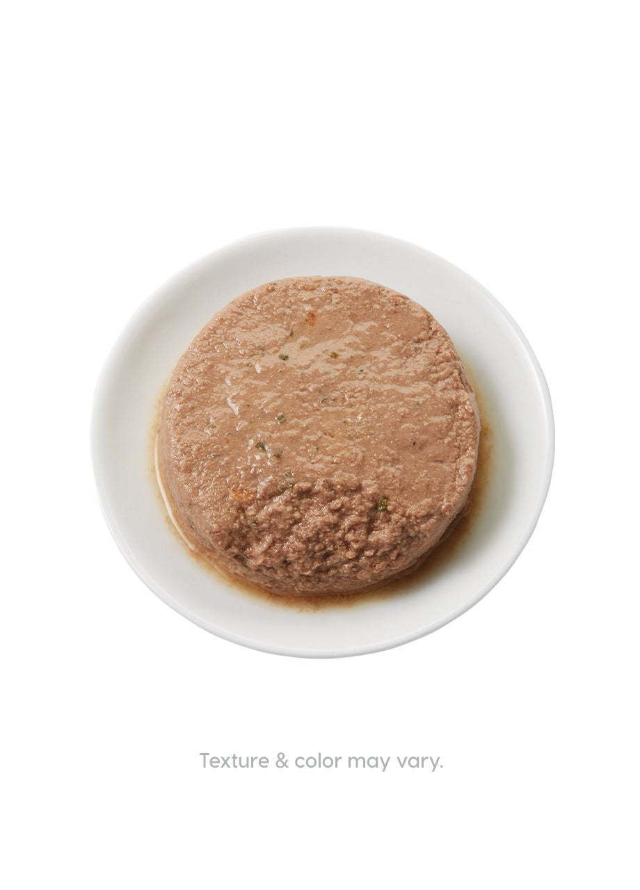 Wet cat food in a round shape on a white plate, with a smooth, moist texture and brown color.