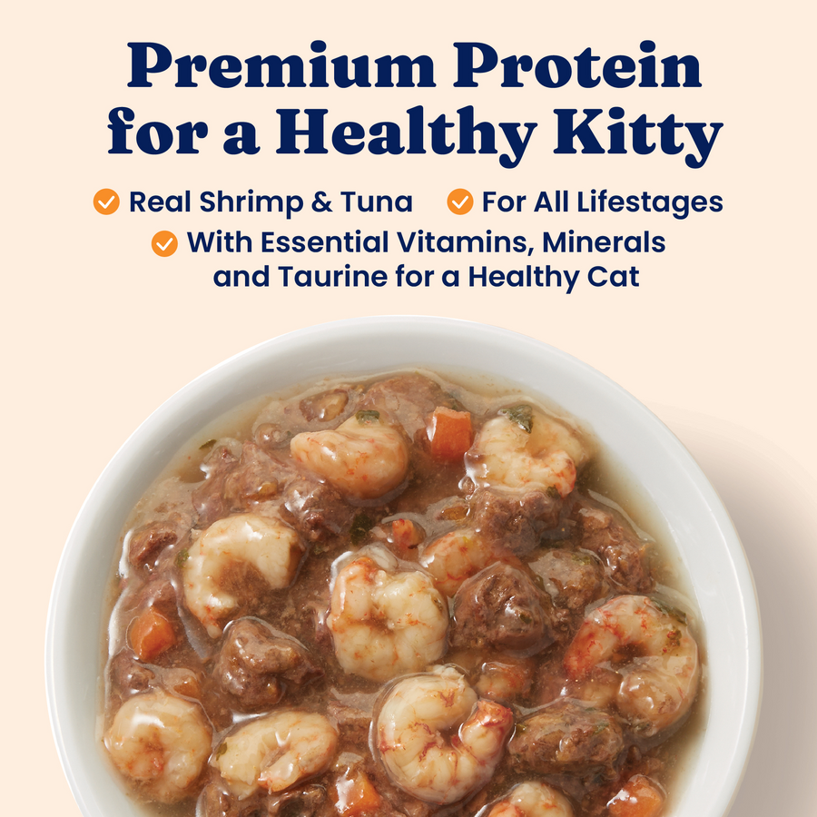 Wet cat food in a bowl featuring shrimp, tuna, and vegetables in a gravy-like sauce.